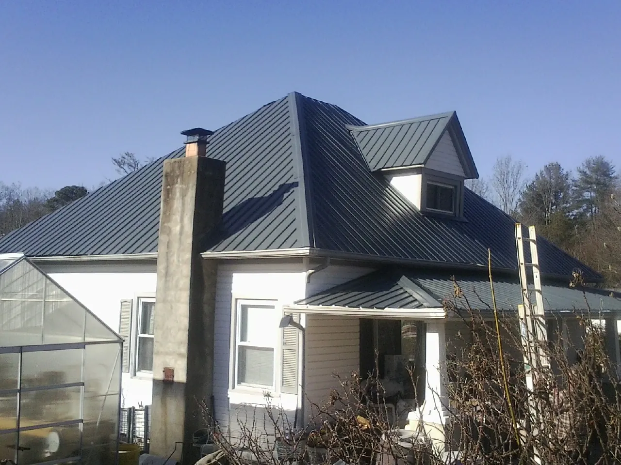 Dark blue standing seam metal roof on a white farmhouse with dormer — Slate & Tile Roof Repair by Roofing Brothers in Waite Park