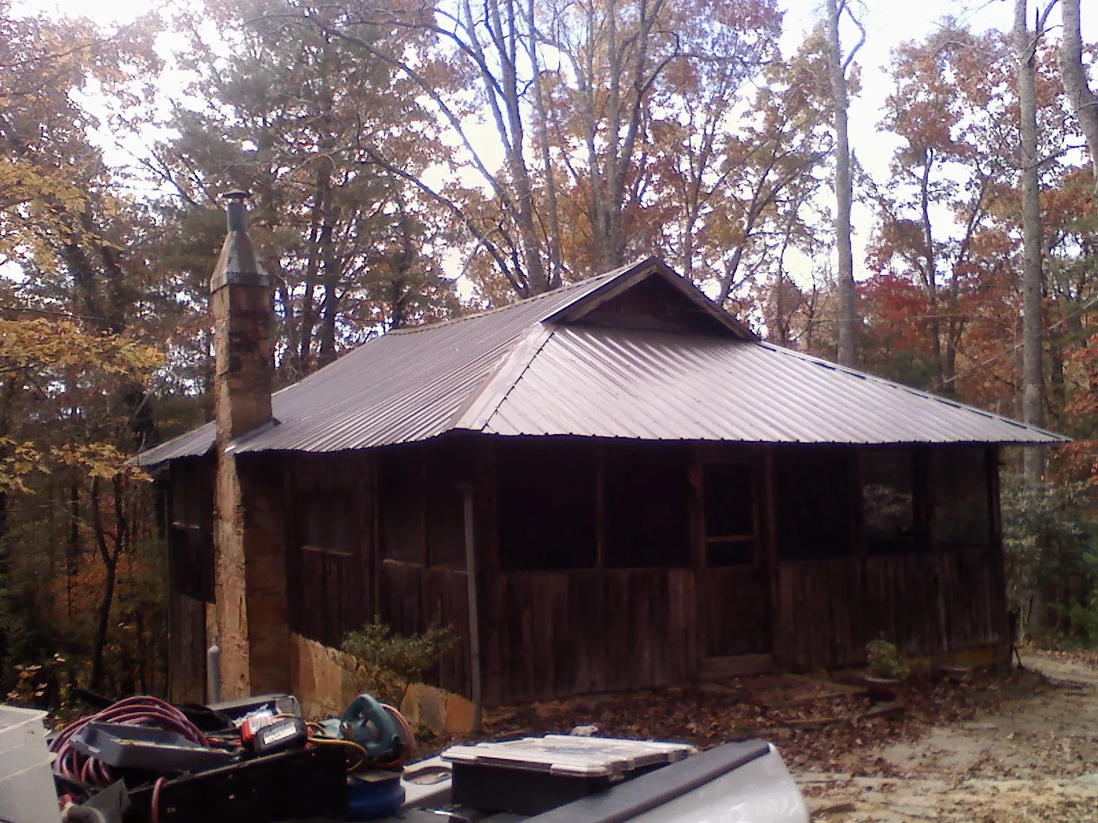 Brown metal hip roof on an old cabin with a stone chimney in Waite Park