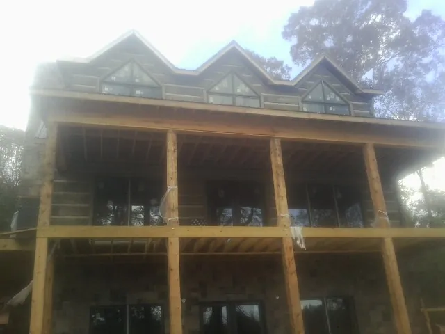 Dormers and porch framing on a large log home under construction — Roof Coating work by our crew in Waite Park