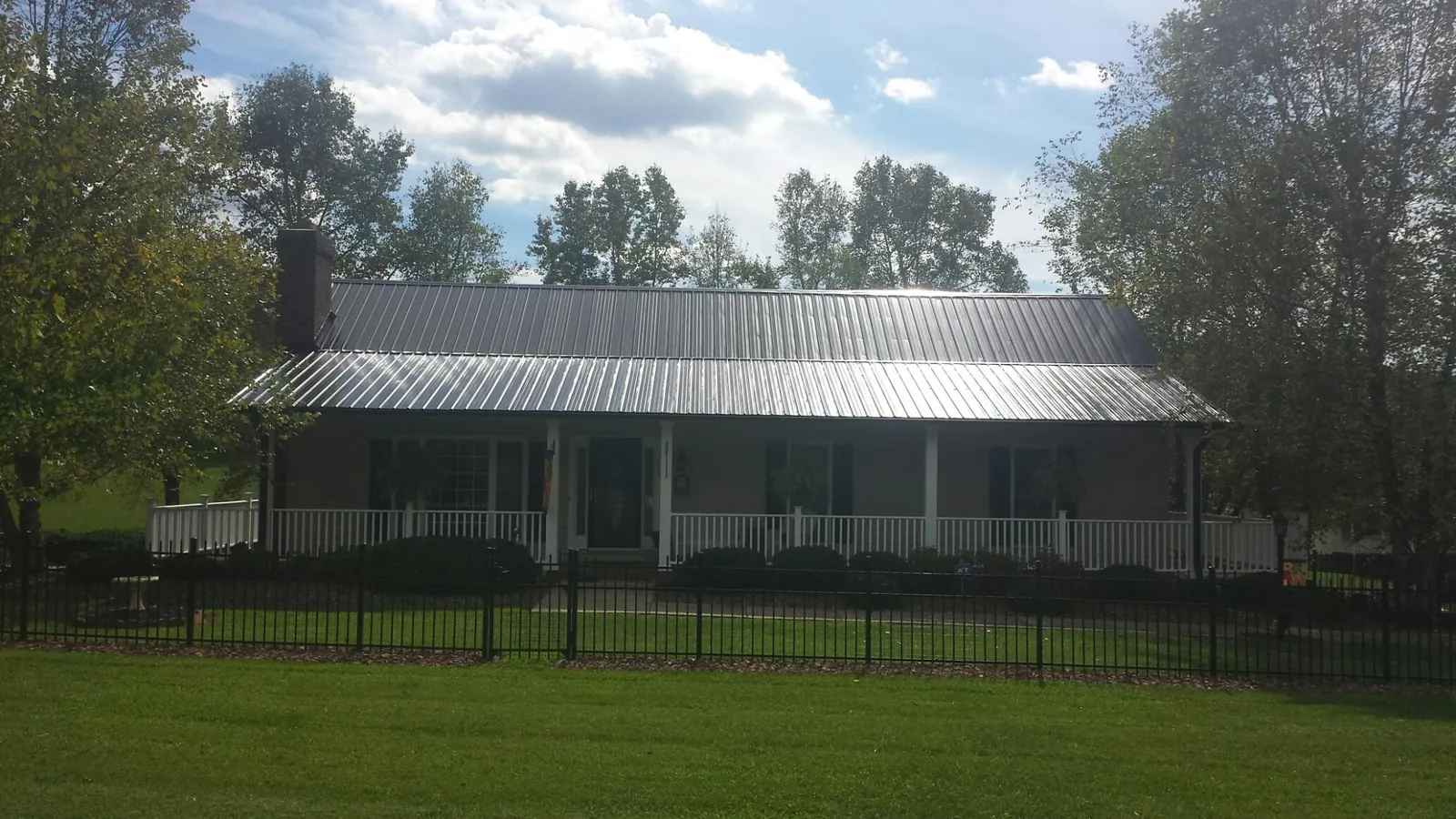 Gray metal roof on a brick ranch with a full width front porch — Gutter Guard Installation work by our crew in Waite Park
