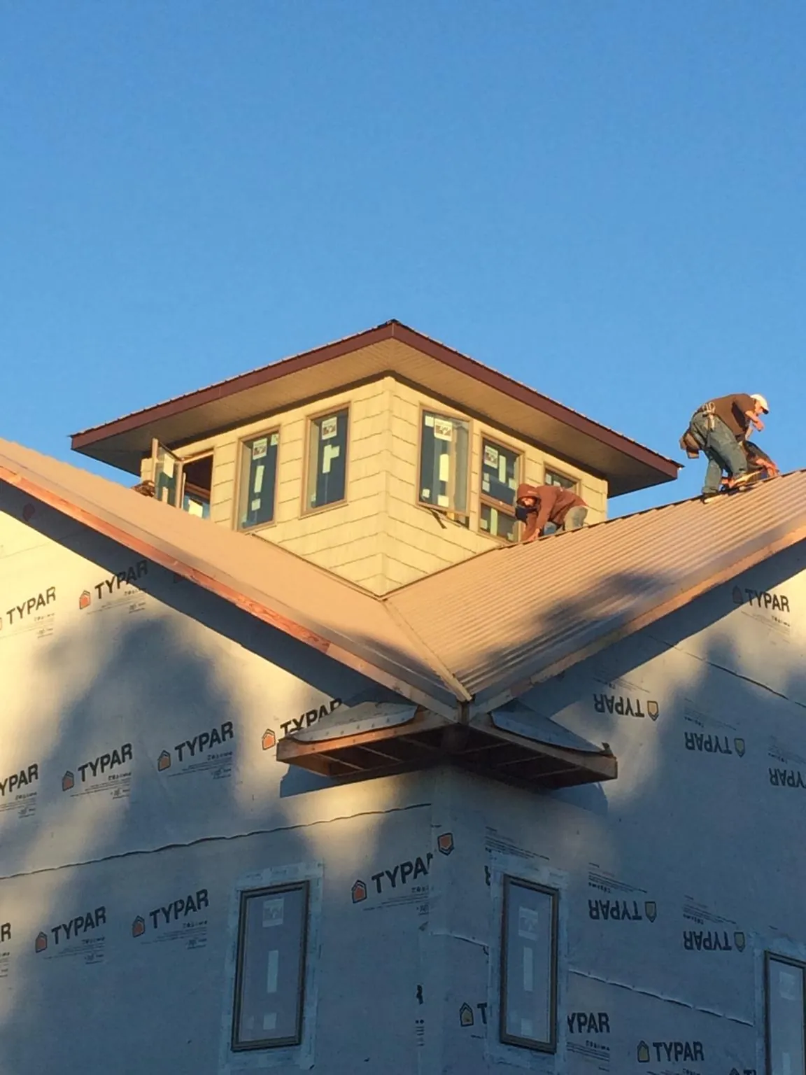 Roofers working around a rooftop cupola on a new metal roof at sunset — Roof Waterproofing in Waite Park by Roofing Brothers